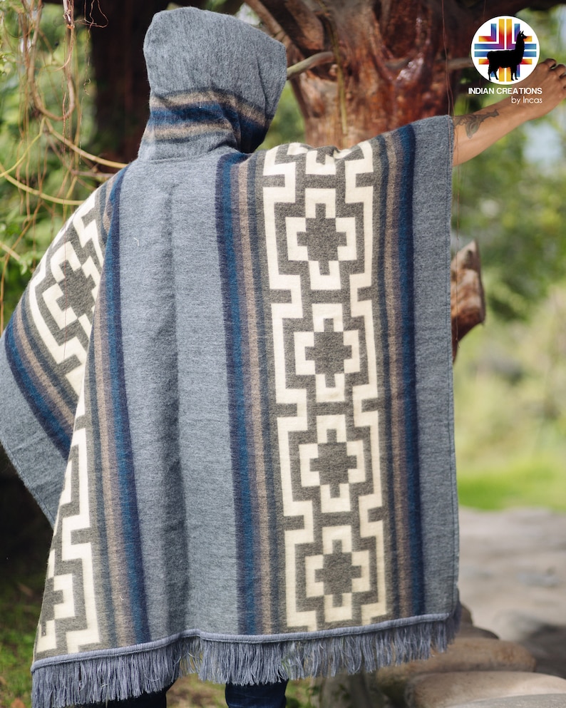 May include: A gray hooded poncho with a geometric pattern in white and black. The poncho has a fringe border and is made of a soft, woven fabric.