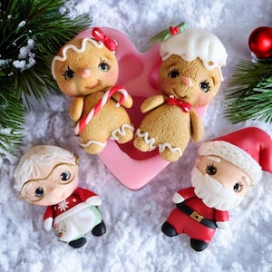May include: Four Christmas-themed figurines made of polymer clay. Two gingerbread people, one with a candy cane and one with a white icing hat, are in a pink heart-shaped mould. A Santa Claus figurine with a white beard and a white-haired woman wearing glasses and a red sweater are on a white snowy surface.