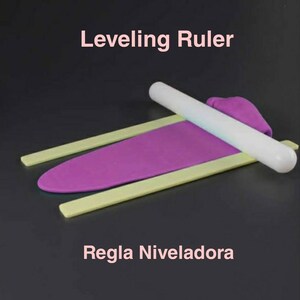 May include: A white acrylic rolling pin with two yellow plastic levelling rulers. The rolling pin is on top of a purple fondant sheet. The text "Leveling Ruler" is at the top of the image and the text "Regla Niveladora" is at the bottom of the image.