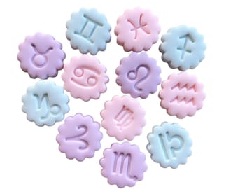 May include: Twelve pastel-colored zodiac signs, each with a different astrological symbol, are arranged in a heart shape. The signs are made of a smooth, rounded material and have a slightly raised design.