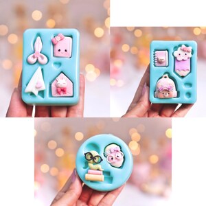 May include: Three silicone molds for making small resin crafts. The first mold has four cavities: a pair of scissors, a small envelope, a paper airplane, and a closed envelope with a bunny on it. The second mold has four cavities: a small book, a cloud with a pencil, a backpack with a bear face, and a pencil. The third mold has two cavities: a book with a worm and a pair of glasses, and a pair of glasses with a bow on top.
