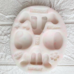 May include: White silicone mold with multiple cavities for making various shapes, including a flower, a leaf, a boot, and a mushroom. The mold is labeled "ANGELY" and "FANXIANG".