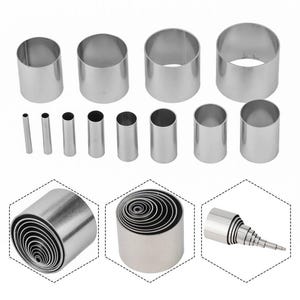 Puede incluir: Conjunto de 18 cortadores de galletas redondos de acero inoxidable en varios tamaños. Los cortadores están dispuestos en una cuadrícula con algunos apilados uno encima del otro.