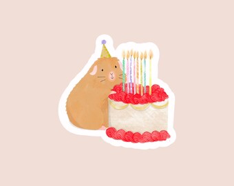 May include: A brown hamster wearing a party hat sits next to a white cake with red frosting and colorful candles.