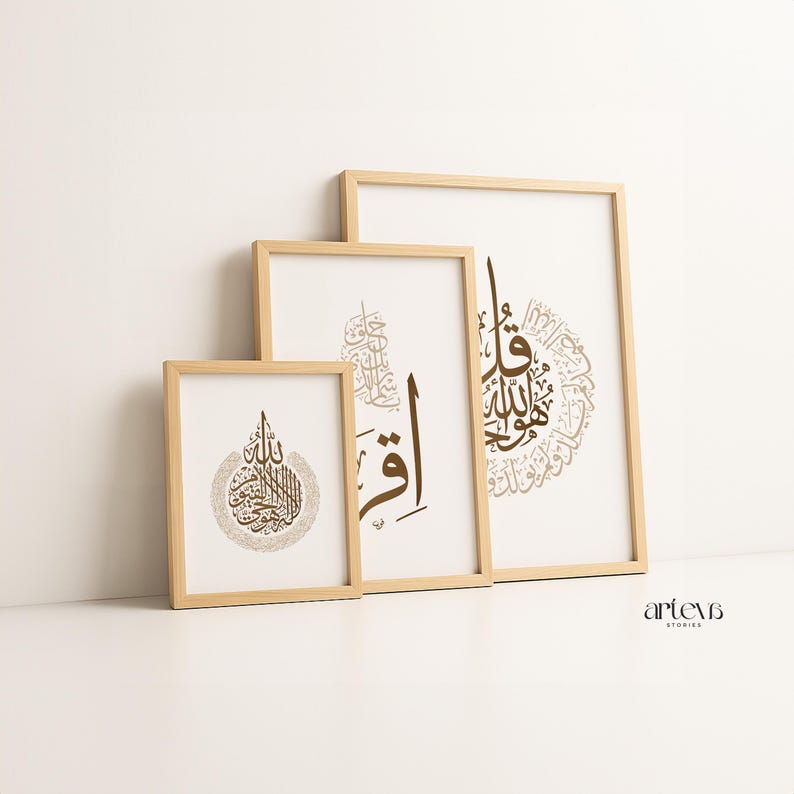 May include: Three framed art prints with Arabic calligraphy in shades of brown and gold. The prints are in wooden frames and are arranged in a leaning display. The background is white, and the overall aesthetic is minimalist and elegant.