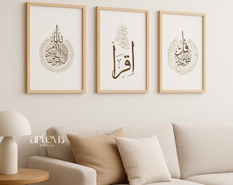 May include: Three framed art prints featuring Arabic calligraphy in brown and gold tones. The prints are displayed above a beige sofa with decorative cushions. The frames are made of light wood, creating a minimalist and elegant aesthetic.