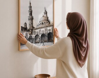 Könnte beinhalten: Ein rechteckiger Wandkunstdruck in einem hellen Holzrahmen mit einer detaillierten Tusche- und Aquarellzeichnung einer Moschee mit einem markanten Minarett und einer Kuppel. Das Kunstwerk zeigt architektonische Bögen in neutralen Farben.