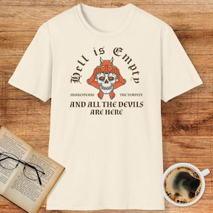 May include: Cream-colored t-shirt with a graphic featuring a devil holding a skull, with the text "Hell is Empty" and "And All The Devils Are Here". The design includes the text "Shakespeare" and "The Tempest".