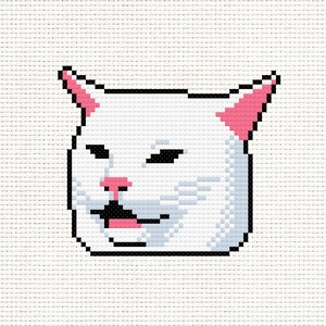 May include: Cross-stitch pattern of a white cat with black and pink accents. The cat's face has a skeptical expression, with its eyes narrowed and mouth slightly open. The design is pixelated, giving it a retro aesthetic.