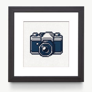 Puede incluir: Un diseño de punto de cruz enmarcado de una cámara vintage con cuerpo azul y lente plateada.