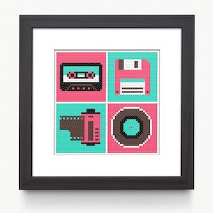 Op de afbeelding: Een ingelijste print met gepixelde afbeeldingen van een cassettebandje, een diskette, een filmrol en een vinylplaat. De afbeeldingen staan tegen een turquoise en roze achtergrond, met een zwarte lijst.