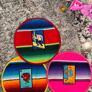 K&ouml;nnte beinhalten: Drei runde, farbenfrohe Untersetzer mit einem Serape-Design und gestickten Bildern von traditionellen mexikanischen Spielkarten. Die Karten zeigen "El Borracho", "La Rosa" und "La Borracha".