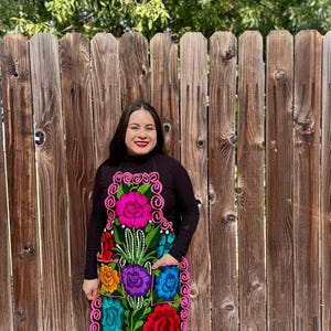 May include: A black apron with a colorful floral embroidery design. The apron has a pink trim and multiple pockets. The text "Model 6" is visible in the lower right corner of the image.