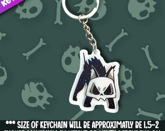 May include: A keychain featuring a stylized black and white cat with a skull-like face. The keychain is attached to a silver chain and ring. The text "KEYCHAIN" is in the upper left corner. The size of the keychain will be approximately 1.5-2 inches maximum in height or width.
