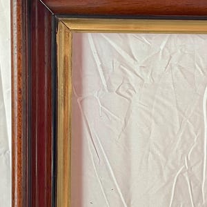 May include: A rectangular wooden picture frame with a dark brown exterior and a gold interior border. The frame has a glossy finish and is empty, with a white background visible inside.