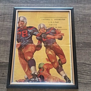 May include: A vintage poster advertising a football game between Laconia and Rochester. The poster features two football players in action, one in a blue and white uniform and the other in a brown and white uniform. The game is scheduled for October 14, 1949 at L.H.S. Field at 8:00 PM.