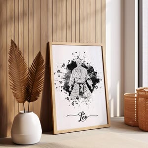 May include: Black and white watercolor illustration of a person in a karate uniform with a white belt. The illustration is surrounded by black splatters of paint. The name "Leo" is written in cursive at the bottom of the image.