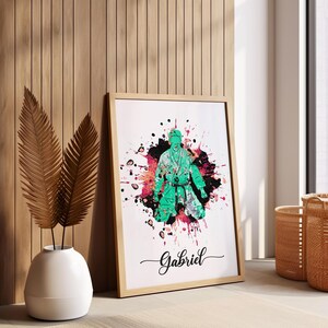 May include: A framed print with a green silhouette of a person in a martial arts pose, surrounded by colorful paint splatters. The name "Gabriel" is written in cursive at the bottom of the print.