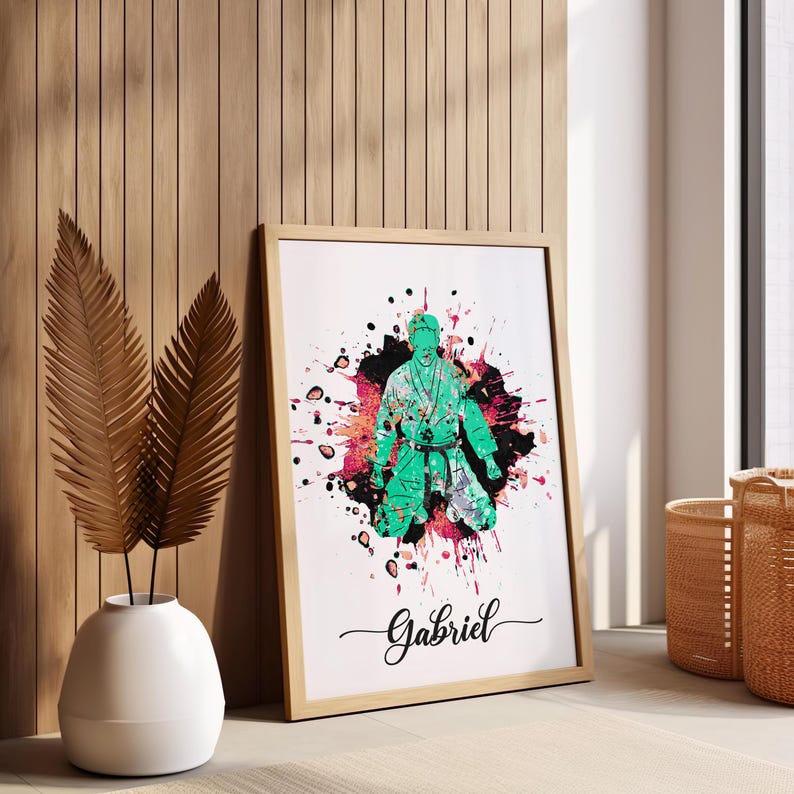 May include: A framed print with a green silhouette of a person in a martial arts pose, surrounded by colorful paint splatters. The name "Gabriel" is written in cursive at the bottom of the print.