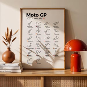 K&ouml;nnte beinhalten: Ein gerahmtes Wandposter mit dem Titel Moto GP 2027 Calendrier, das ein Raster aus schwarzen Linienzeichnungen von Rennstrecken mit L&auml;ndernamen und Flaggen zeigt. Es steht auf einem Holzm&ouml;bel neben drei B&uuml;chern, einer braunen Vase und einer roten Lampe.