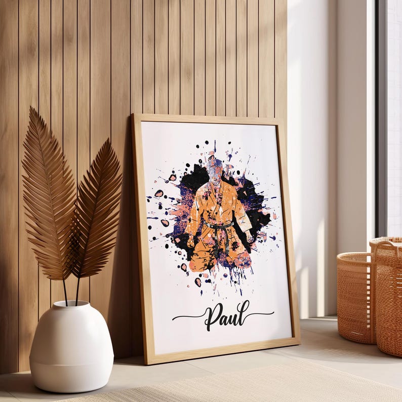 May include: A framed print of a person in a karate uniform with a splash of colorful paint behind them. The name "Paul" is written in cursive at the bottom of the print.