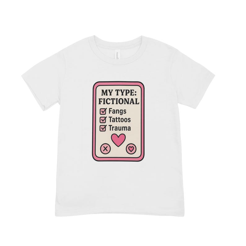 Może przedstawiać: Biała koszulka z napisem "MY TYPE: FICTIONAL" z polami wyboru dla "Fangs", "Tattoos" i "Trauma". Projekt zawiera r&oacute;wnież r&oacute;żowe serce i inne symbole.