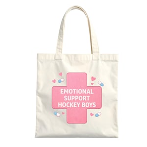 Puede incluir: Bolso tote color crema con un dise&ntilde;o de cruz rosa. La cruz contiene el texto "EMOTIONAL SUPPORT HOCKEY BOYS" en blanco. Peque&ntilde;os corazones rosas y c&aacute;psulas azules y blancas decoran el dise&ntilde;o.