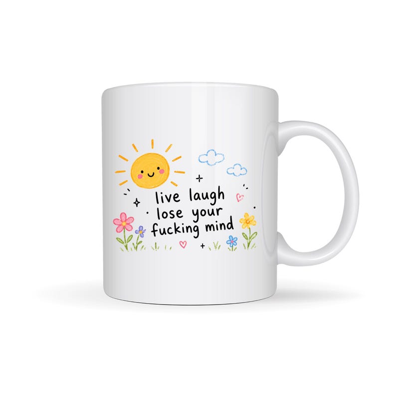 Puede incluir: Taza de cer&aacute;mica blanca con un dise&ntilde;o caprichoso. La taza presenta un sol sonriente, nubes, flores y el texto "live laugh lose your fucking mind". La taza tiene un asa curvada.