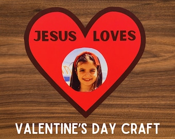 Puede incluir: Un corazón rojo con un contorno negro y las palabras "JESUS LOVES" en su interior. Una foto de una niña está en un círculo dentro del corazón. Las palabras "VALENTINE'S DAY CRAFT" están debajo del corazón.