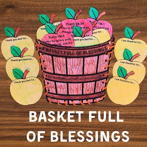 May include: A wooden basket filled with paper apples, some pink and some yellow, with green leaves. The basket has the words "A Basket Full of Blessings" and Bible verses. The words "Thank you God for..." and "I am thankful for..." are on the apples.