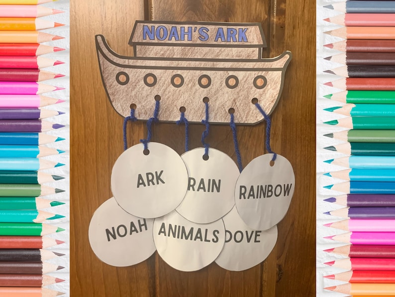 K&ouml;nnte beinhalten: Eine braune Papierbastelarbeit von Noahs Arche mit blauer Schnur, die von oben h&auml;ngt. Die Schnur ist an wei&szlig;en Kreisen befestigt, auf denen die W&ouml;rter "ARK", "RAIN", "RAINBOW", "NOAH", "ANIMALS" und "DOVE" stehen.