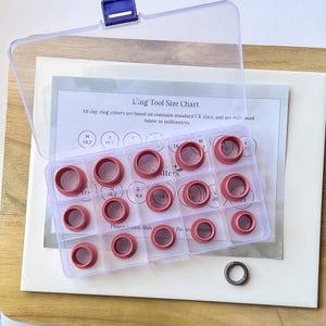 May include: A clear plastic storage case containing a set of 15 red clay ring cutters. The case has a chart labelled "King Tool Size Chart" listing sizes in millimetres.