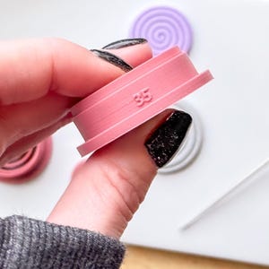 May include: Pink plastic cookie cutter with a spiral design and the number 35 printed on it.
