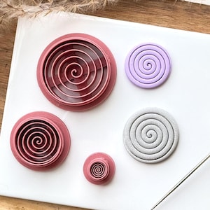 May include: Set of five pink and grey plastic cookie cutters in various sizes, each featuring a spiral design.
