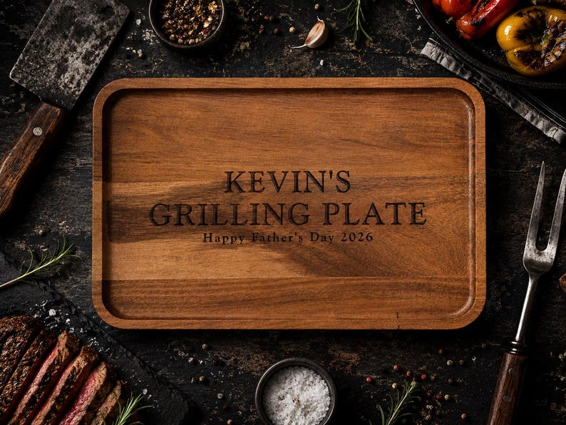 May include: A rectangular wooden serving tray with rounded corners and a raised edge. The center is engraved with the text KEVIN'S GRILLING PLATE and Happy Father's Day 2026 in a dark, sans-serif font, showcasing the natural brown wood grain.