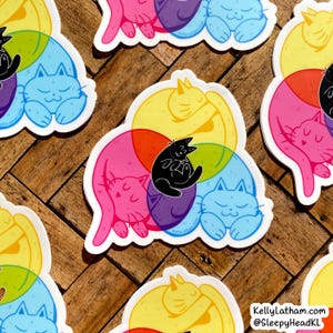 May include: Four colorful stickers featuring a group of cats cuddling together in a circle. The cats are in different colors, including pink, yellow, blue, and purple. The stickers are designed with a playful and whimsical style, perfect for adding a touch of personality to any surface.