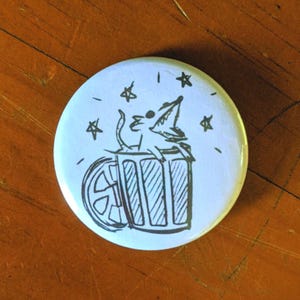 May include: A white button with a black and white illustration of a cat in a trash can with stars around it.