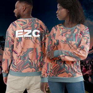 Puede incluir: Dos personas vistiendo una sudadera de color melocotón con un patrón abstracto azul y verde. La sudadera tiene el texto "EZC" impreso en la parte posterior en blanco.
