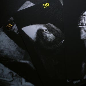 May include: Close-up of several black playing cards with gold numbering. The cards feature a grayscale illustration of a person with a long beard. The number 30 is visible on one card, and the number 31 is visible on another.