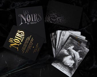 May include: A collection of tarot cards and boxes. The boxes are black with silver and gold lettering that reads "LES NOIRS OF ODILON." The cards feature black and white illustrations. The overall aesthetic is dark and mysterious.