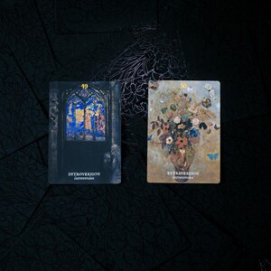 May include: Two tarot cards with dark backgrounds. One card features a stained-glass window with the word "Introversion" and the number 49. The other card shows a floral arrangement with butterflies and the word "Extraversion" and the number 50.