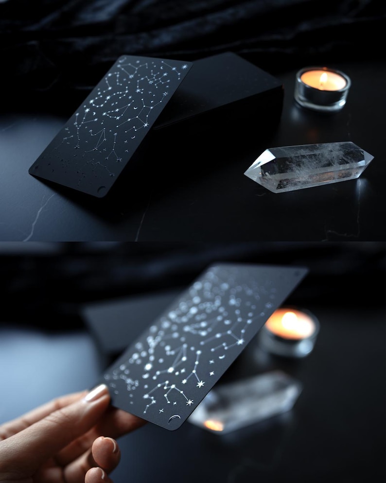 May include: Black tarot card with a constellation design in white. A clear quartz crystal and a lit candle are also visible. The card is held in a hand in one of the images. The background is dark.