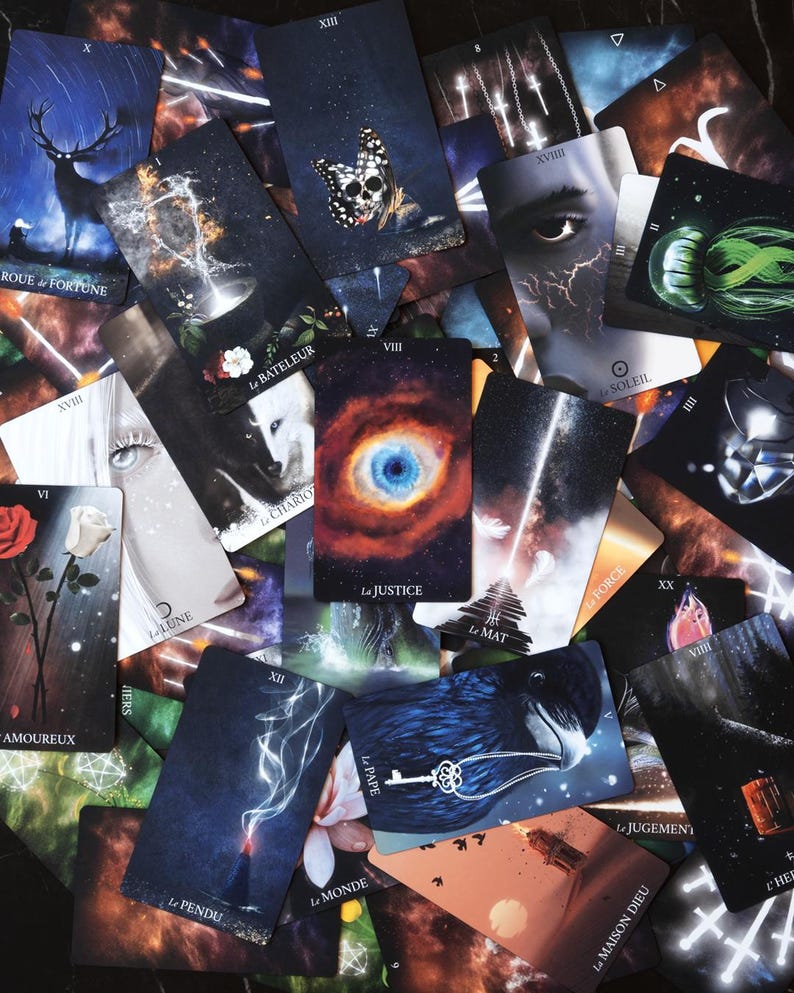 May include: A collection of tarot cards with various mystical illustrations. The cards feature images of a deer, a butterfly skull, an eye, and other symbolic imagery. Some cards have French text, including "La Justice" and "Le Monde."
