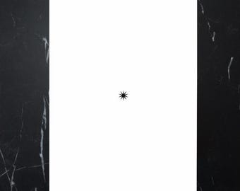 May include: A white rectangular card with a small black starburst design centered on the card. The background is a black marble pattern.
