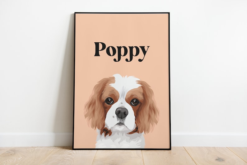 May include: A peach-colored poster with a black border features a cartoon illustration of a Cavalier King Charles Spaniel dog with brown and white fur. The dog's name, "Poppy", is printed in black at the top of the poster.