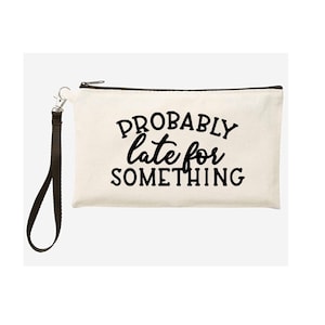 May include: A white canvas zippered pouch with a black strap. The pouch has black text that reads "PROBABLY late for SOMETHING."