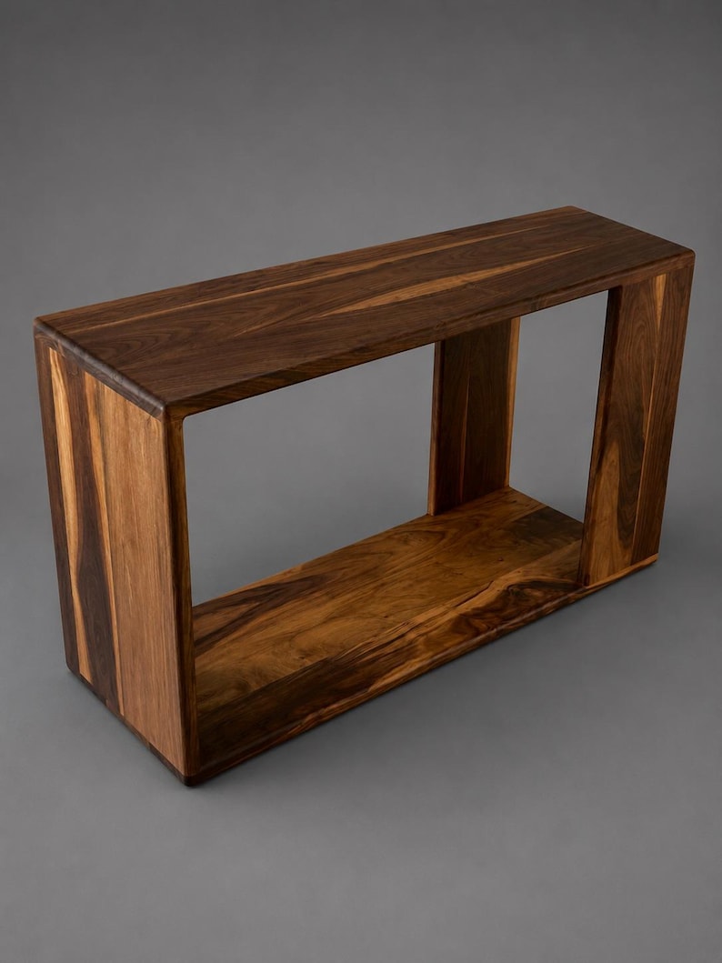 May include: A rectangular console table constructed from dark brown wood with a visible natural grain pattern. The piece features a hollow, open-frame design with a flat top surface, two vertical side panels, and a flat bottom base.