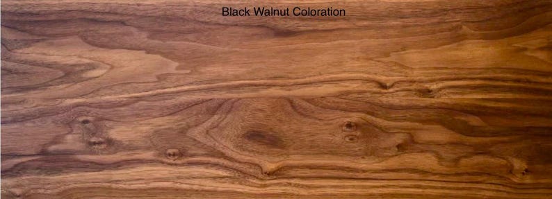 May include: A rectangular piece of wood featuring a rich brown Black Walnut coloration with prominent natural grain patterns, swirling wood knots, and organic dark brown streaks running horizontally across the smooth, polished surface.