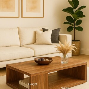 May include: A rectangular wooden coffee table with a smooth brown finish, featuring an open lower shelf and a solid top surface. The table has labels indicating its height, width, and depth dimensions. It is positioned on a light-colored rug.