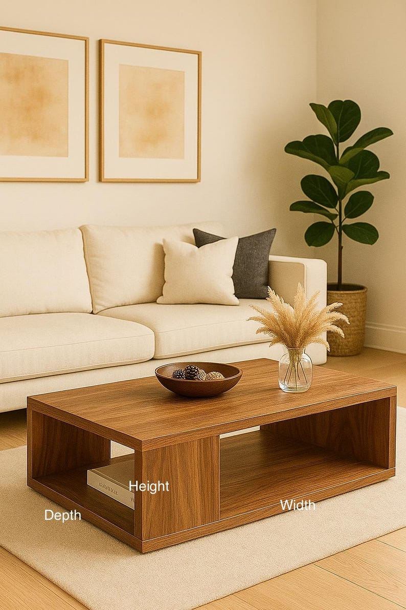 May include: A rectangular wooden coffee table with a smooth brown finish, featuring an open lower shelf and a solid top surface. The table has labels indicating its height, width, and depth dimensions. It is positioned on a light-colored rug.